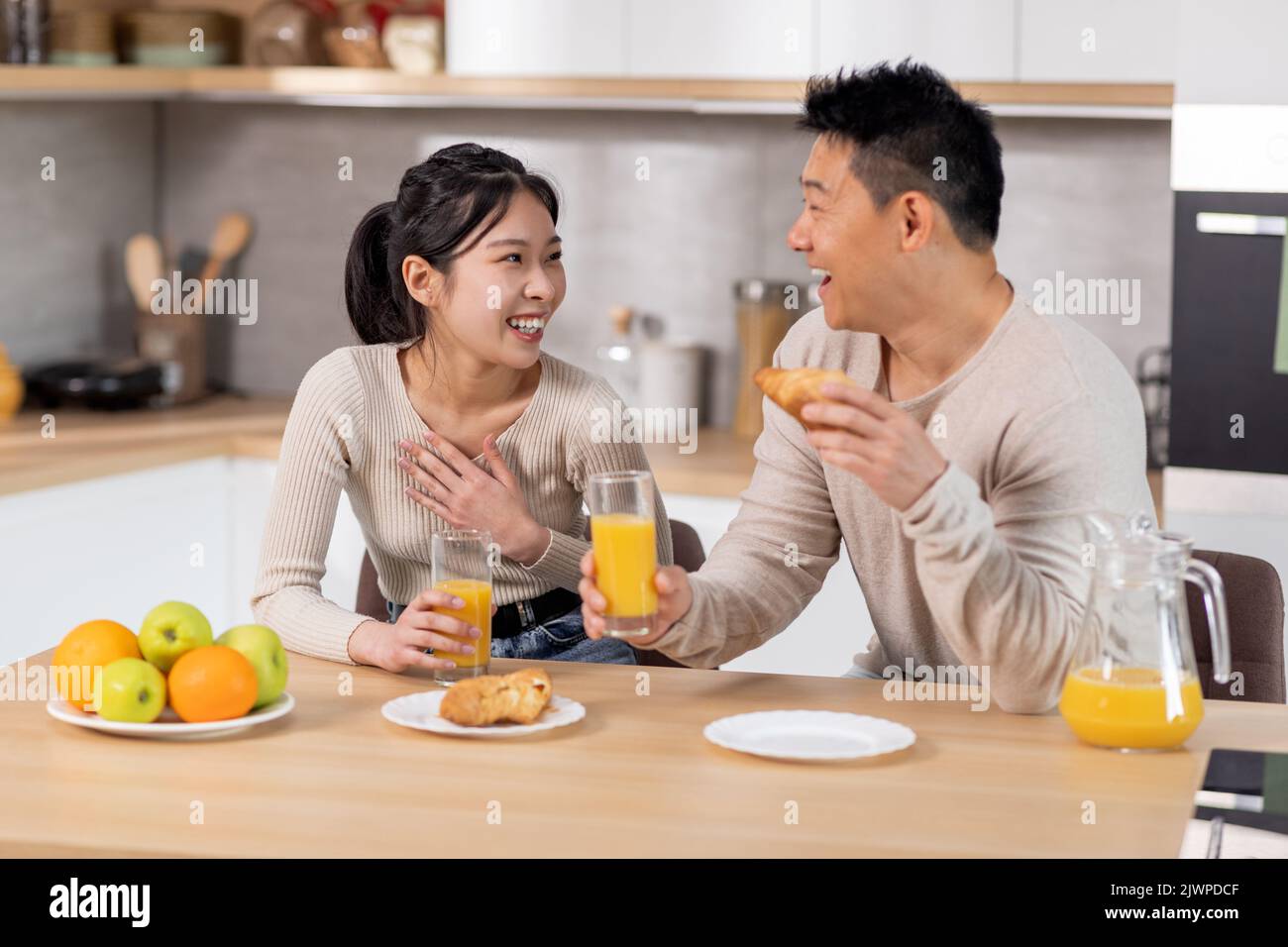 sposi giapponesi positivi che si divertono mentre mangiano in cucina Foto Stock