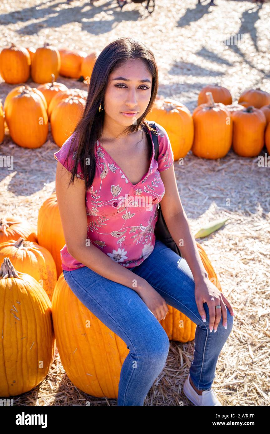 Ritratto della festa autunnale di giovane donna asiatica seduta su una grande zucca in una fattoria Foto Stock