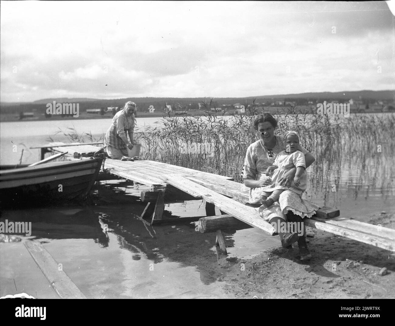 La famiglia Brundin affittò una residenza manageriale in estate alla fonderia di Lingbo, che si trova su un bellissimo lago chiamato Lingan, dove avevano un molo e una barca. Qui Marta Brundin siede con un bambino, forse Margareta. Familjen Brundin hyrde sommartid en dissonentbostad till gjuteriet i Lingbo, som ligger vid en vacker sjö som heter Lingan, där man hade en brygga och båt. här sitter Marta Brundin med något fienile, kanske Margareta. Foto Stock