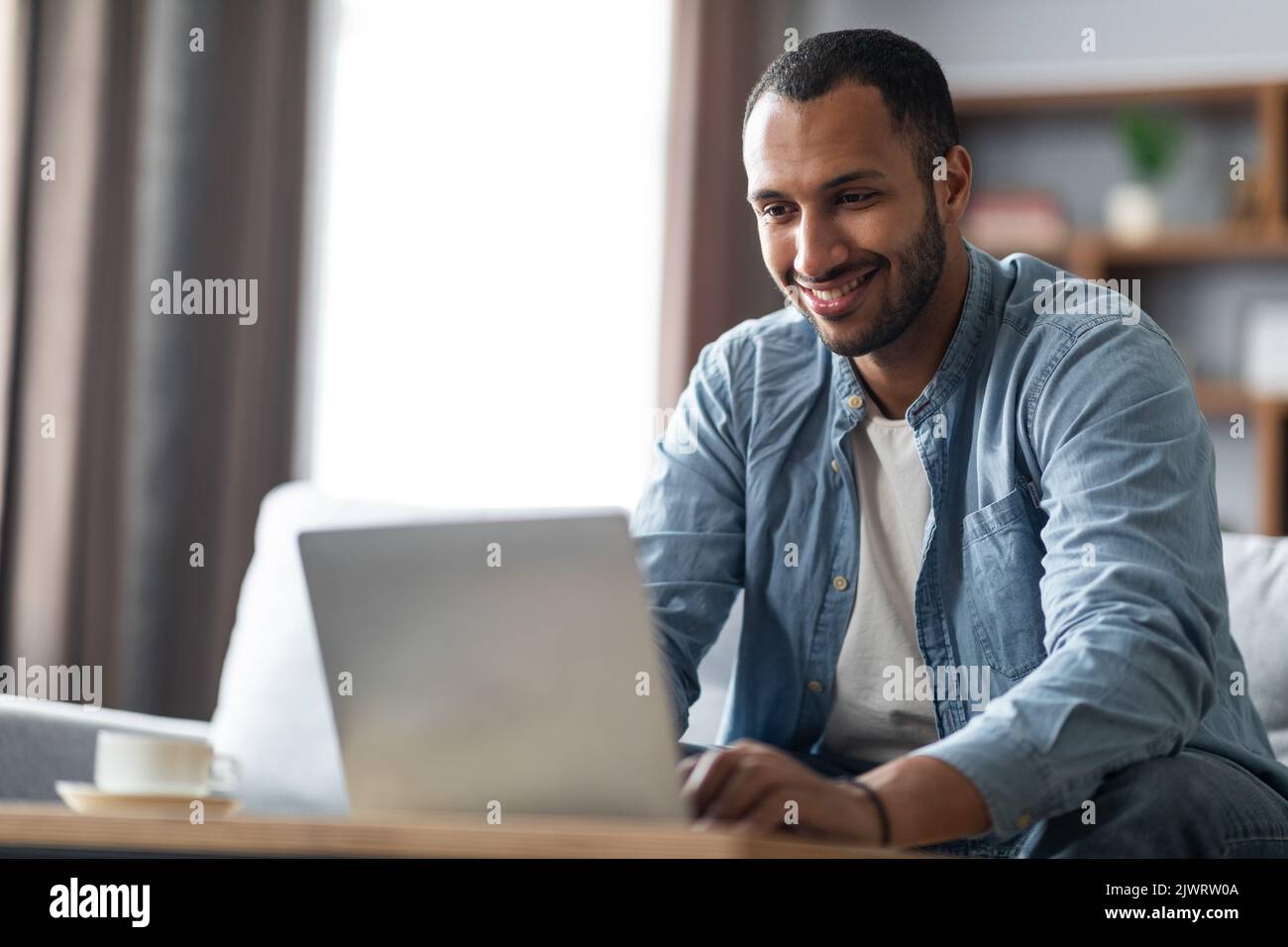 Ufficio remoto. Ritratto di un bel ragazzo nero che lavora con un notebook a casa Foto Stock