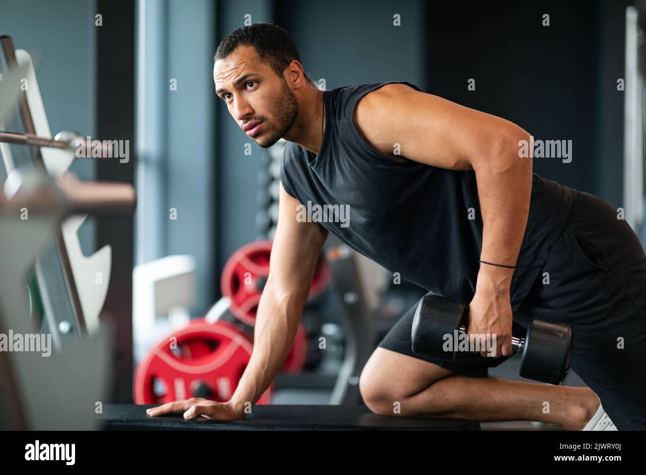 Bell'allenamento di atleta nero maschile con campana a Modern Gym Interior Foto Stock