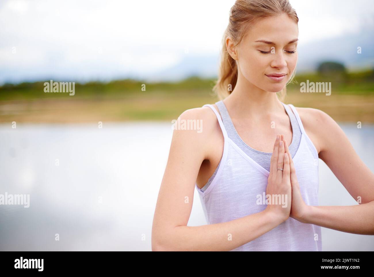 Più si diventa tranquilli, più si sente. Una giovane donna sportiva che tiene le mani in posizione di preghiera. Foto Stock