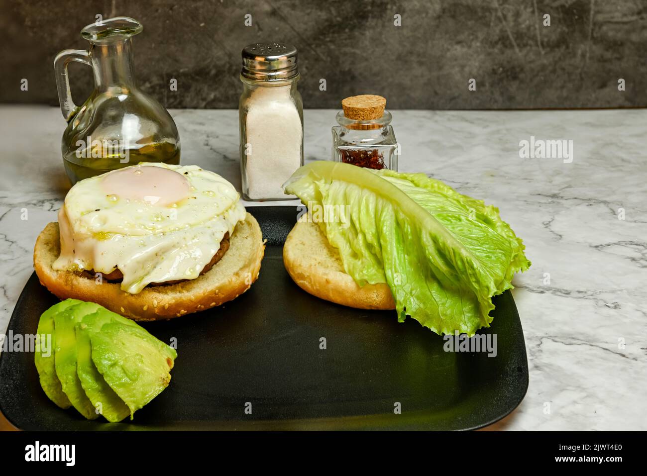 Hamburger con uova fritte, lattuga e avocado. Foto Stock