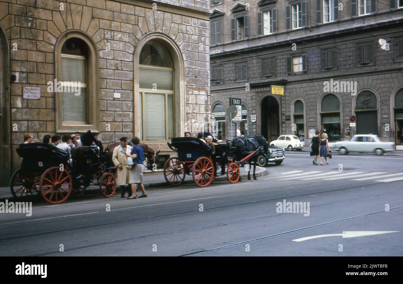 Roma, Italia, 1963. Turisti seduti a bordo di carrozze trainate da cavalli Botticella, in attesa di essere portati in un tour della città. Foto Stock