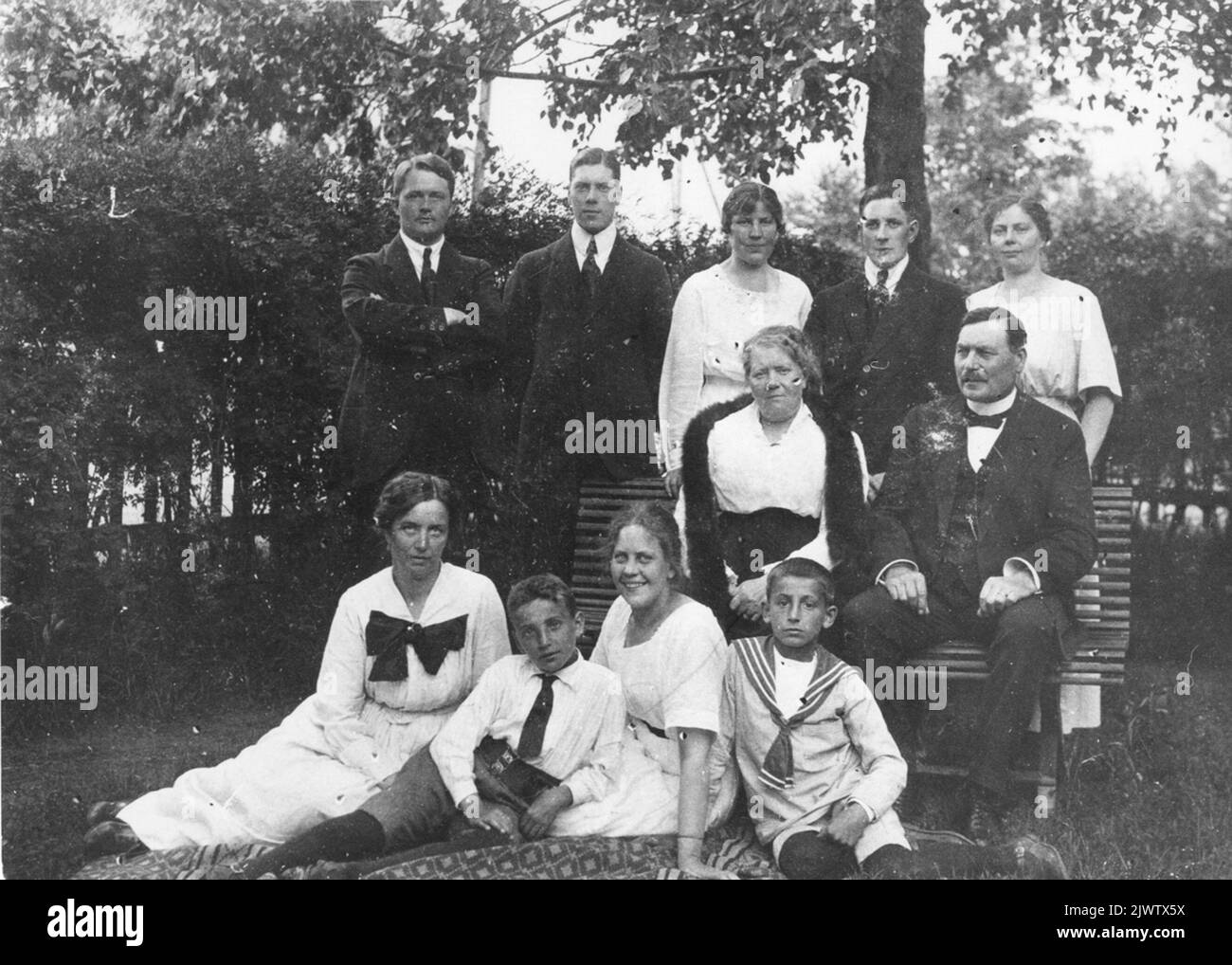 Nel Lundemos Garden, 1920s. Östberg, Torsten Lundemo, Ruth Lundemo, Ivan Lundemo, vera Lundemo. Nel divano la signora Anna e il marito Peder Lundemo, commerciante di Hybo per molti anni, erano di famiglia norvegese. Sulla terra da. Signora Lager, ragazzo tedesco, Ragnhild Lundemo, ragazzo tedesco. I Lundemos trädgård, 1920-tal.Stående fr.v. Östberg, Torsten Lundemo, Rut Lundemo, Ivan Lundemo, vera Lundemo. I soffan FRU Anna och maken Peder Lundemo, handlare i Hybo i många år, var av norsk släkt.på marken fr.v. FRU Lager, pojke tysk, Ragnhild Lundemo, pojke tysk. Foto Stock