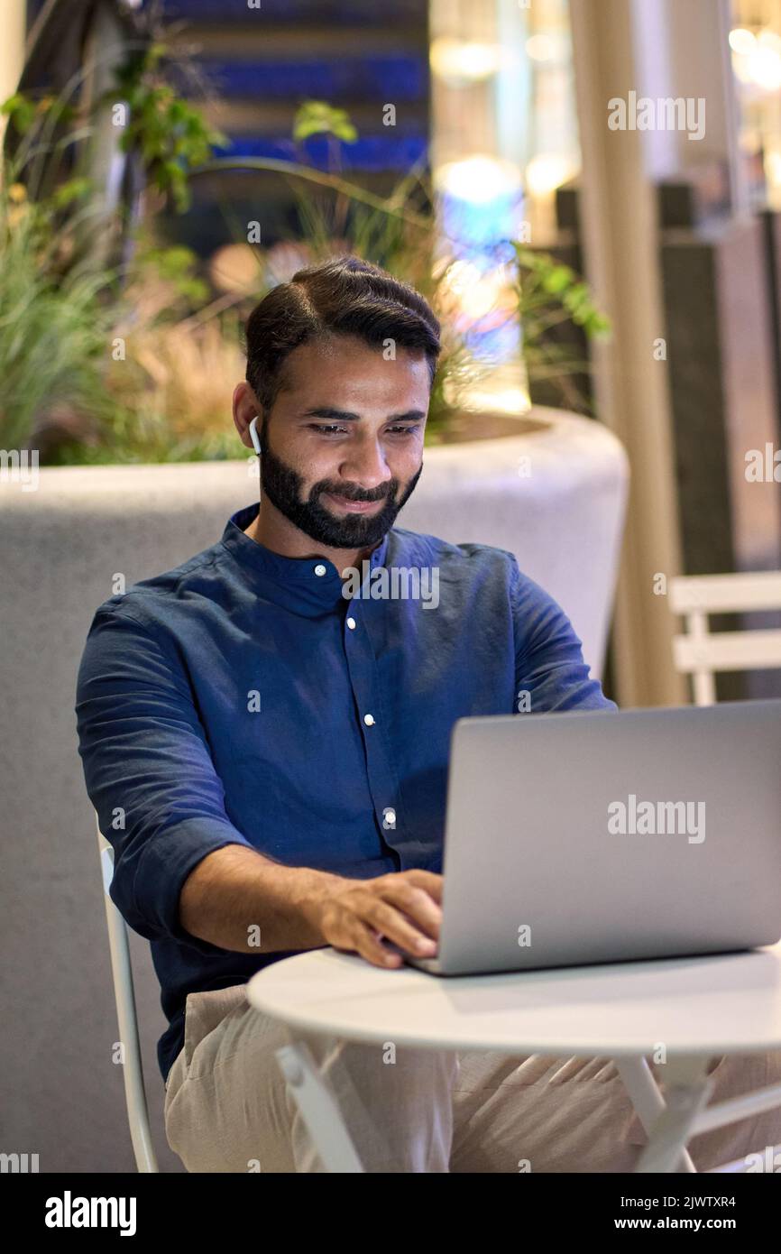 Uomo d'affari indiano che videochiama con un computer portatile nel parco notturno della città. Foto Stock