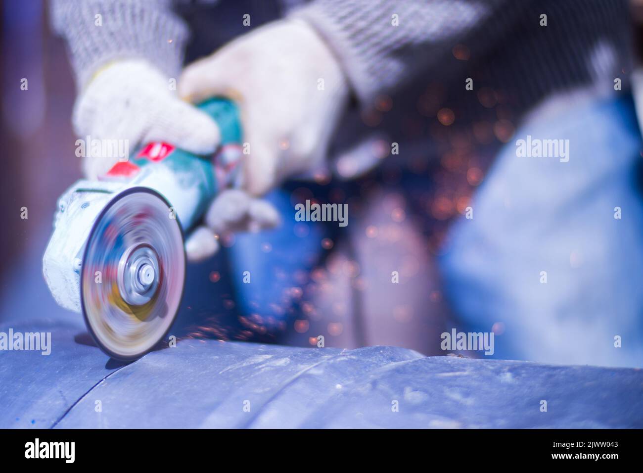 Uomo che lavora con la sega a tazza, vista ravvicinata sull'utensile. Sega elettrica e mani di lavoratore con scintille. Lavoro di taglio del metallo con macinacaffè Foto Stock