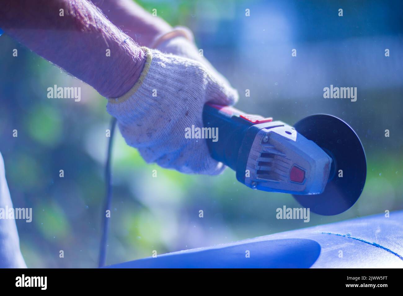 Uomo che lavora con la sega smerigliatrice, vista ravvicinata dell'utensile. Sega elettrica e mani di lavoratore con scintille. Lavoro di taglio con smerigliatrice Foto Stock