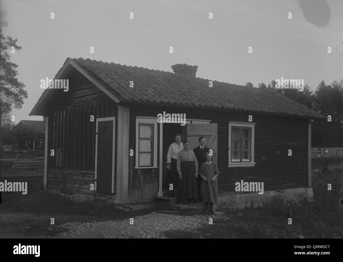 Quattro persone di fronte a un piccolo cottage. Fyra personer framför en liten stuga. Foto Stock