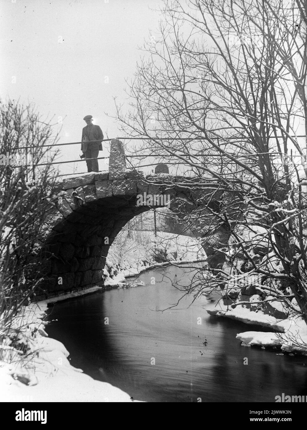 Vecchia strada di campagna. Il vecchio ponte sul fiume a Åsmundshyttan, è stato demolito durante l'ascesa del fiume nel 1928. Sul ponte si trova Enok Eriksson, fotografo dilettante collega e vicino di Bertil Hansson che ha scattato la foto. L'immagine è inclusa nella Torsåkers Photo-Historical Company. Figura 7: 5. Gamla landsvägen. Den gamla bron över ån i Åsmundshyttan, den revs vid omgrävningen AV ån 1928. på bron står Enok Eriksson, amatörfotografkollega och granne fino a Bertil Hansson som har tagit bilden. Bilden finns med i Torsåkers Fotohistoriska Sällskap. Bild 7:5. Foto Stock