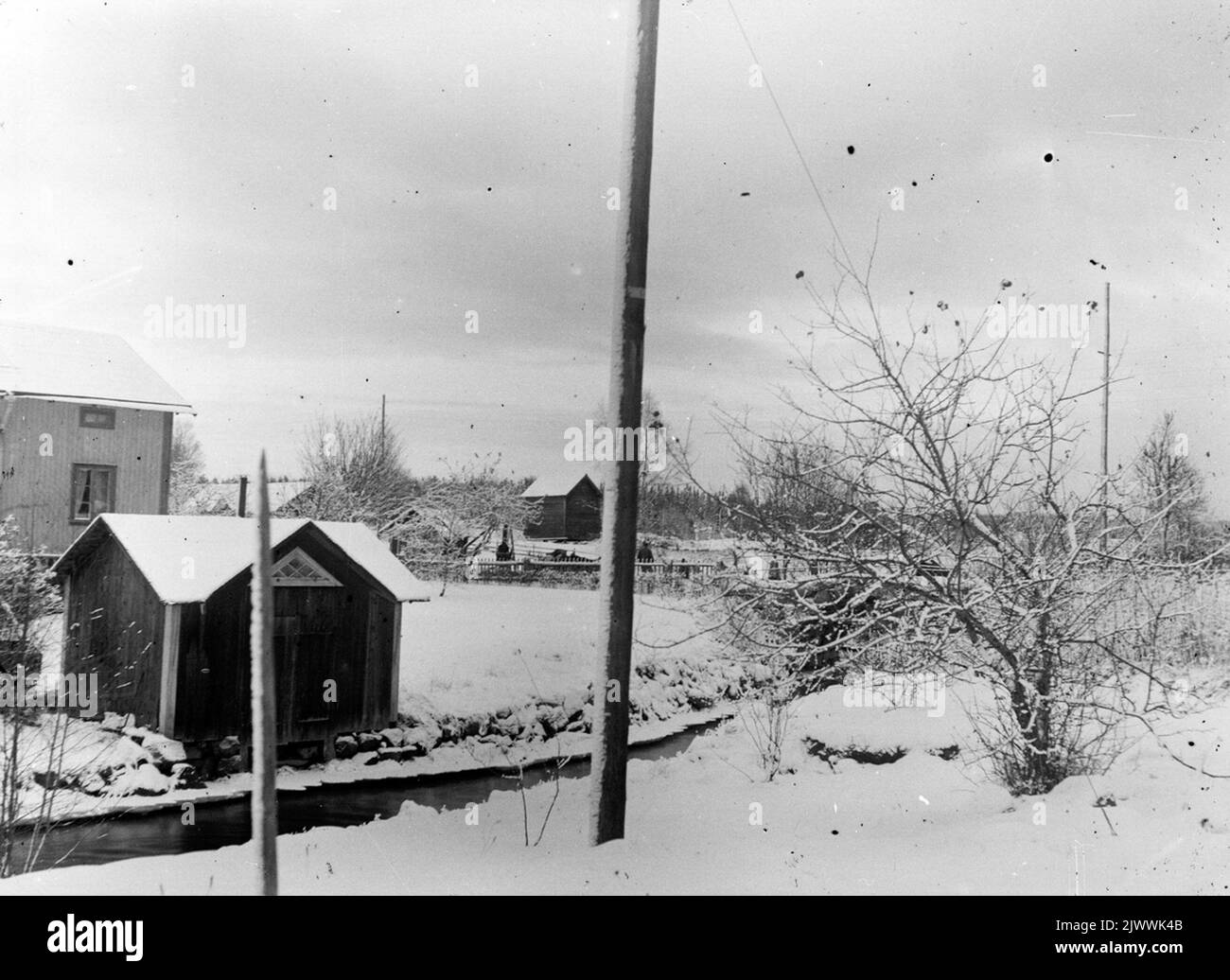 Lo scavo è iniziato ma non è venuto a distruggere lo specchio d'acqua per Åsmundshyttan numero 2 'Erkas'. Ora il fiume è solo un fosso profondo. 'Riconosciuto' Lilla Gård e lavanderia a sinistra e una vecchia rivista sullo sfondo che è stato demolito nel 1950. Ågrävningen har startat men har ej kommit up och förstört vattenspegeln för Åsmundshyttan nummer 2 'Erkas'. Nu är ån endast ett djup dike. 'Erkas' lilla Gård och tvättstuga till vänster och ett gammalt magasin i bakgrunden som revs 1950. Foto Stock