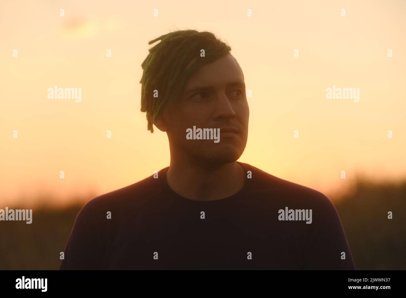 Giovane bell'uomo con greggi che si posano contro il cielo al tramonto Foto Stock