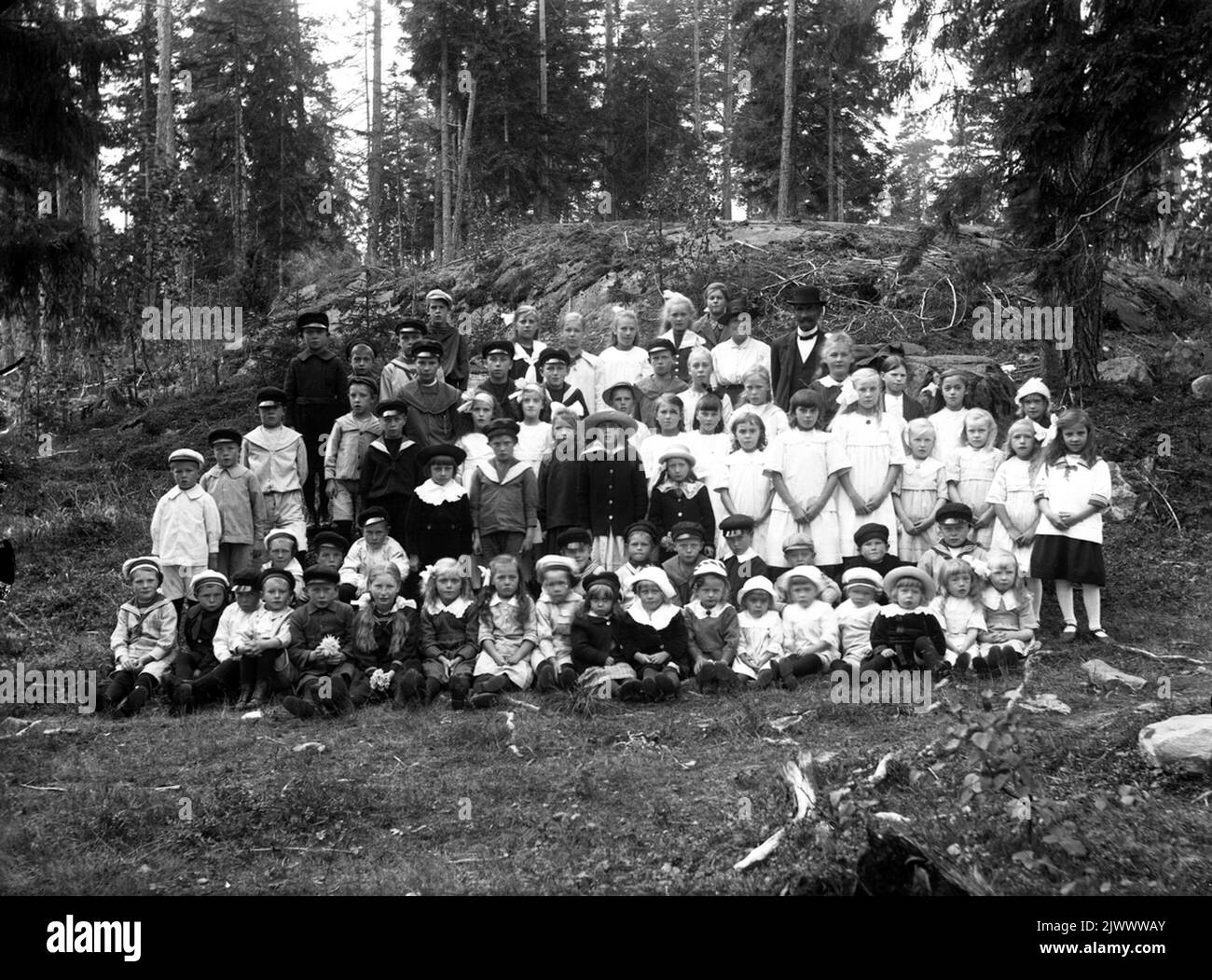 Insegnante con una collezione di studenti scolastici, probabilmente in un'escursione nella foresta. Lärare med en samling skolelever, troligtvis på utflykt i skogen. Foto Stock