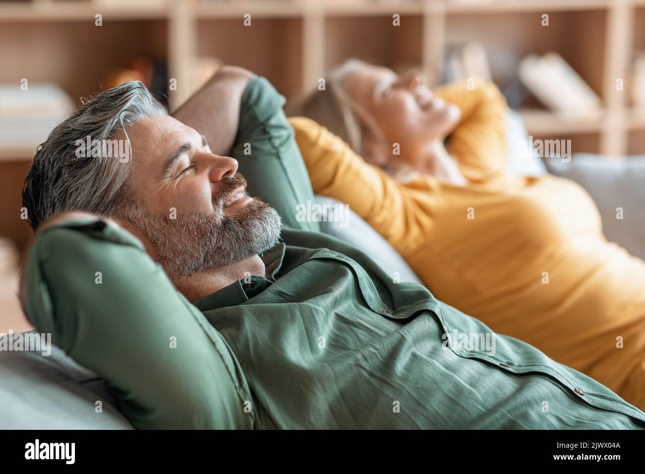 Sorridente Coppia di mezza età che si rilassa insieme su un comodo divano a casa Foto Stock
