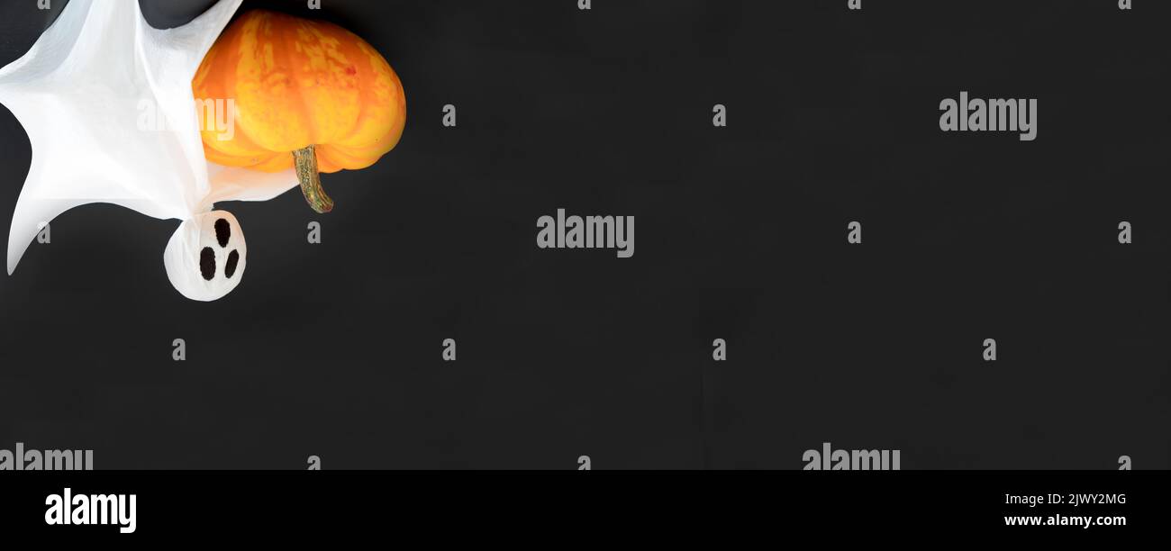 Tre fantasmi bianchi tengono la zucca arancione su sfondo nero. Posa piatta, spazio di copia, banner, concetto di Halloween Foto Stock