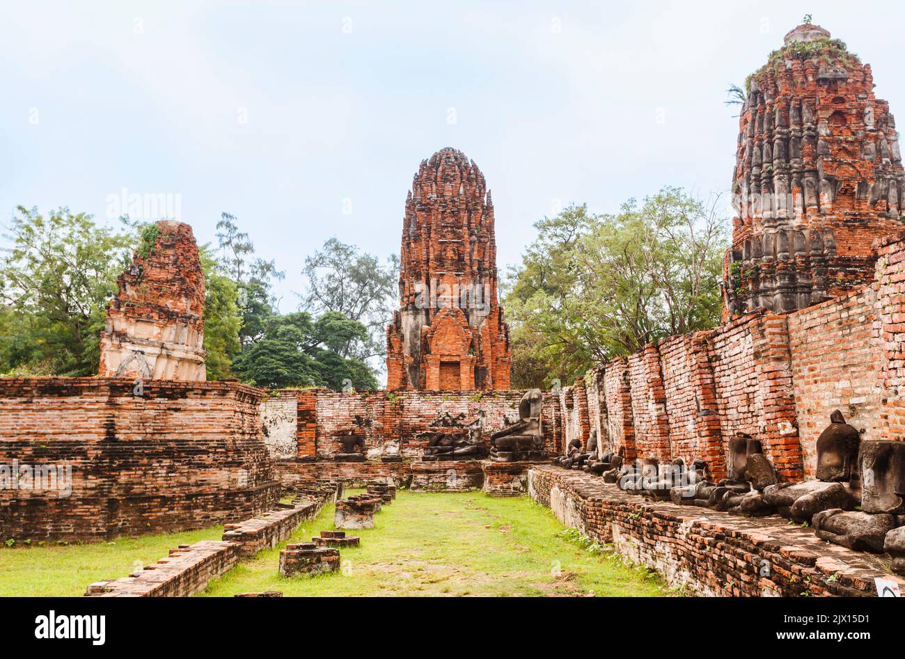 Fatiscenti prangs di mattoni rossi e pareti con statue di Buddha senza testa nelle rovine di Wat Maha That, il sacro tempio reale di Ayutthaya, Thailandia Foto Stock