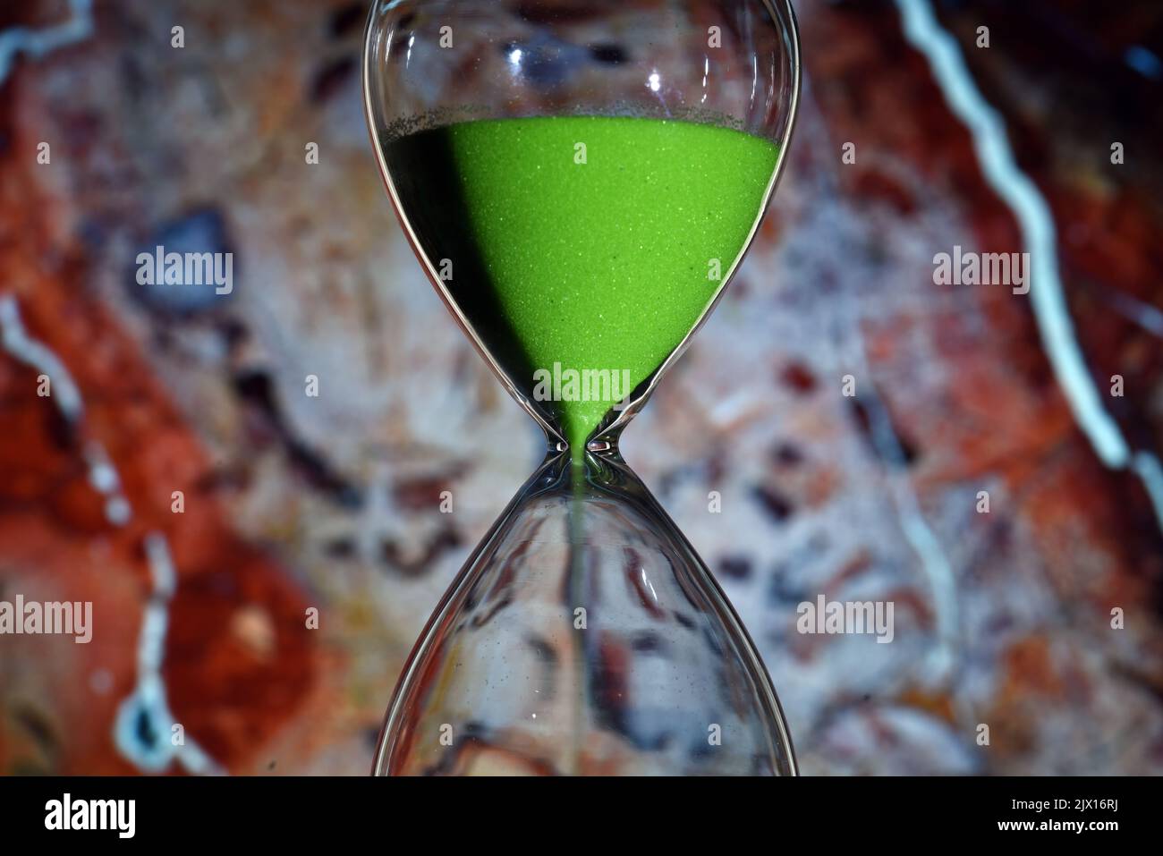 Le reloj de l'arena de color verde, contando el tiempo, sobre diferentes fondos Foto Stock