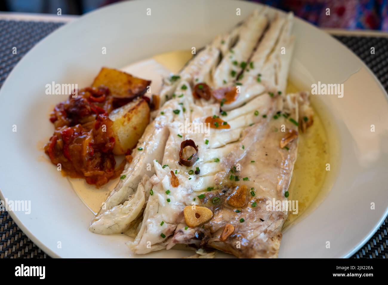 Mangiare in ristorante di fresco alla griglia con aglio e olio d'oliva su vecchio carbone parrillas pesce branzino bianco pesce nel piccolo villaggio di pescatori Getaria, Ba Foto Stock