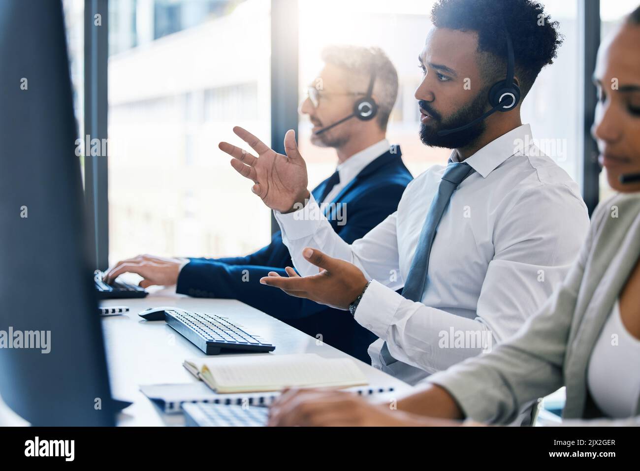 Call center, assistenza clienti e supporto con un consulente tecnico in una cuffia che lavora su un computer in ufficio. Contattateci, crm e telemarketing con Foto Stock