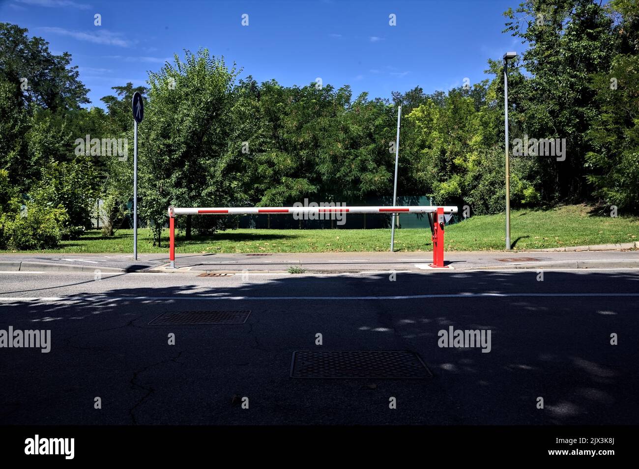 Bar che blocca un passaggio sul marciapiede di una strada di campagna in una giornata di sole Foto Stock