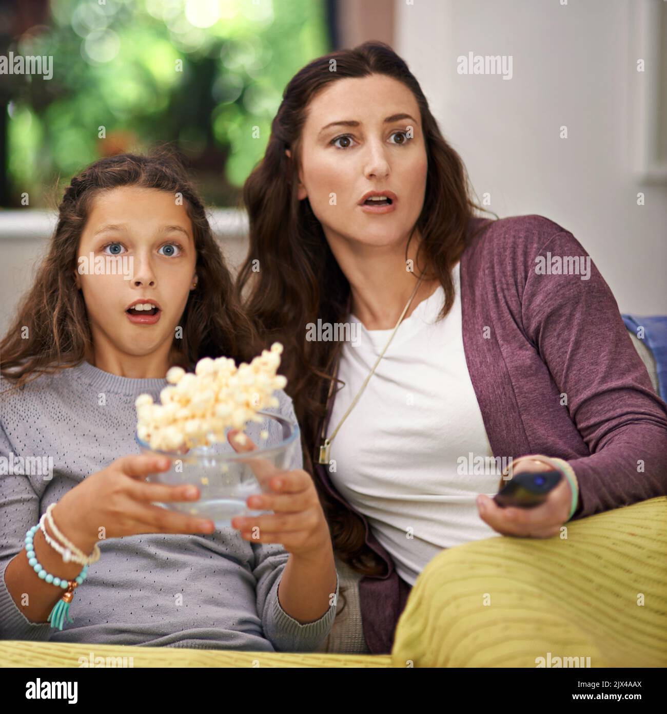 OMG. Una madre e una figlia seduti sul divano del loro soggiorno guardando un film e mangiando popcorn. Foto Stock