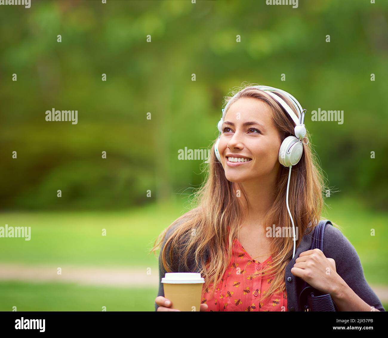 Una giovane donna che ascolta la musica mentre si fa un caffè in viaggio. Foto Stock