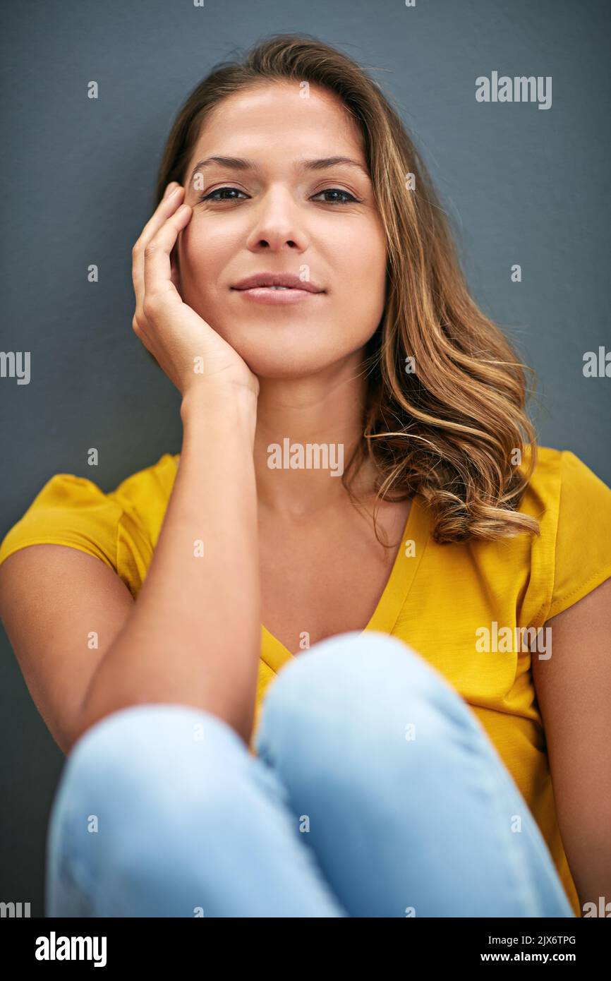 Il relativo appena me. Una giovane donna che si posa contro un muro grigio. Foto Stock