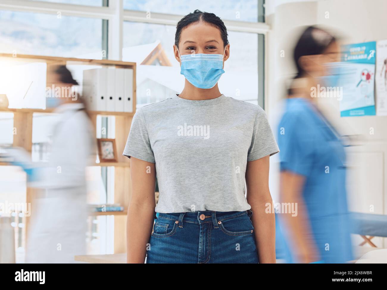 Conformità, assistenza sanitaria e regole covid in ospedale con un paziente felice venire per un controllo con medici impegnati. Ritratto di una giovane donna che guarda Foto Stock