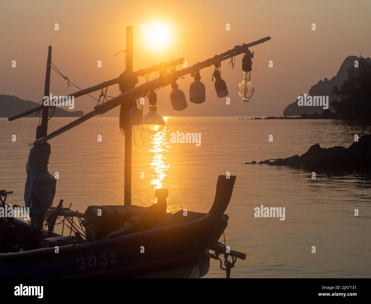 una barca da pesca ferma sulla costa al tramonto Foto Stock