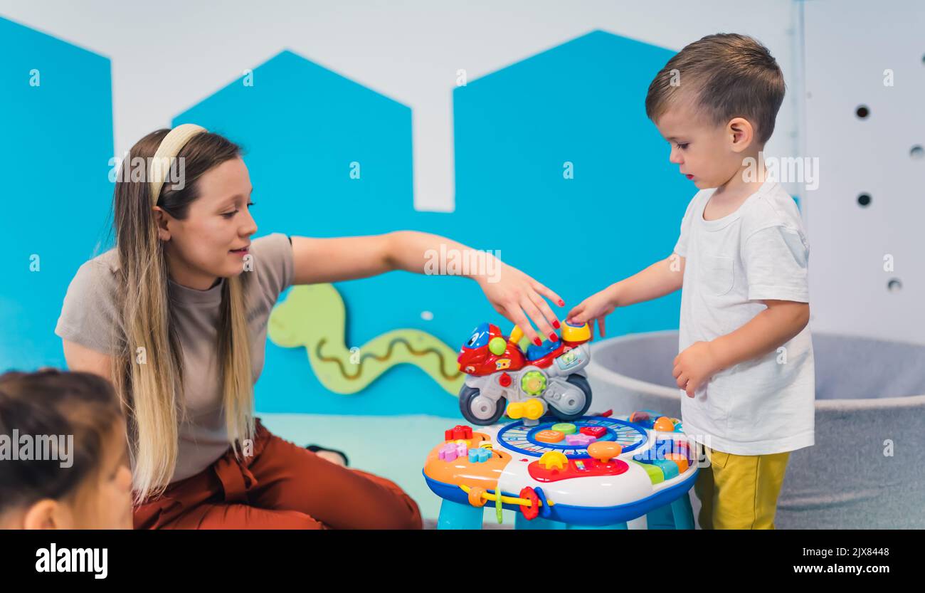 Tempo di gioco alla scuola materna. I bambini con il loro insegnante giocano con colorati giocattoli sensoriali educativi. Interazione con gli altri, sviluppo di abilità critiche per tutta la vita, pratica decisionale. Foto di alta qualità Foto Stock