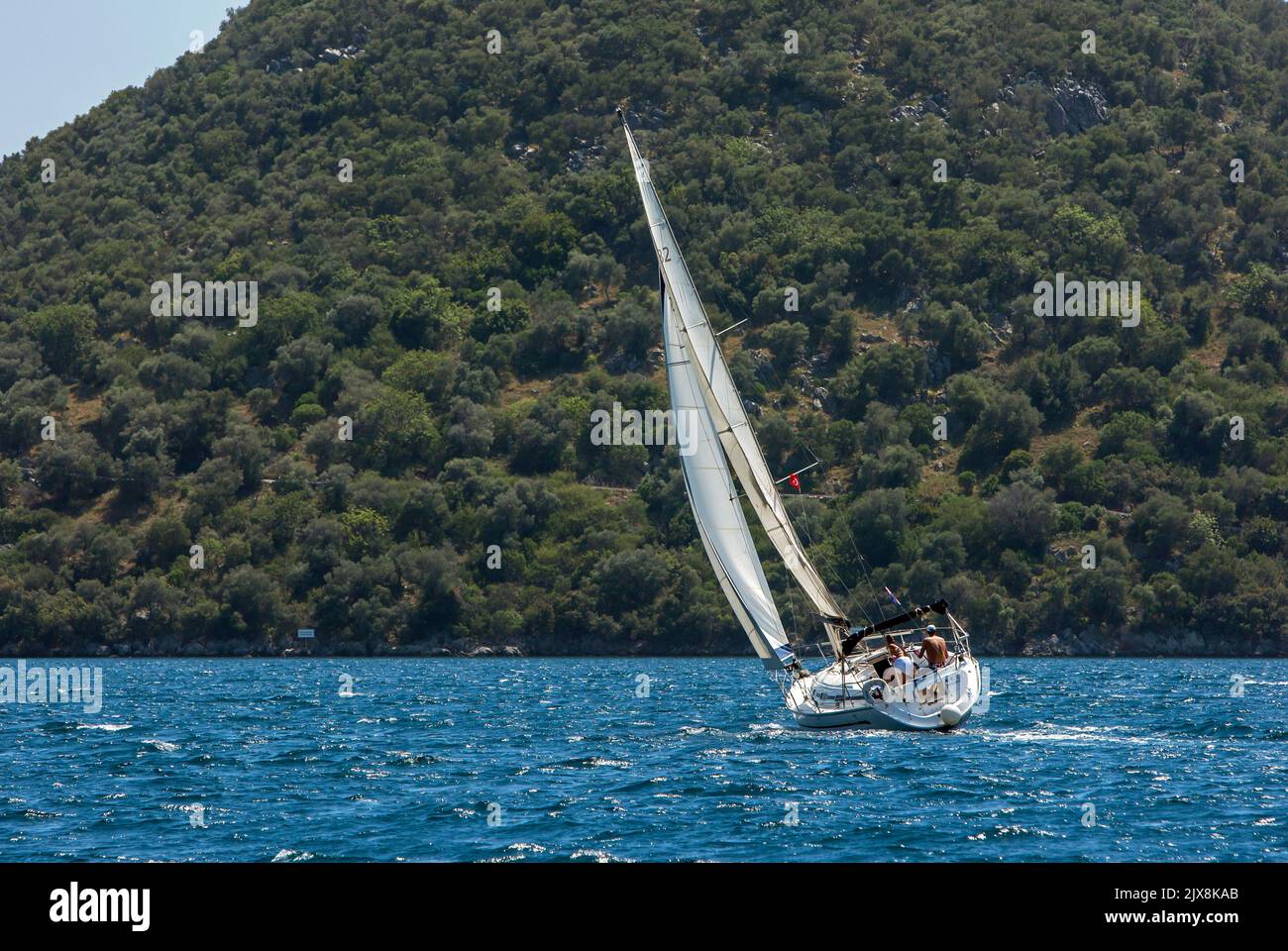 Uno yacht a vela manovra nel Mar Egeo al largo della costa turchese della Turchia vicino alla città portuale di Fethiye. Foto Stock