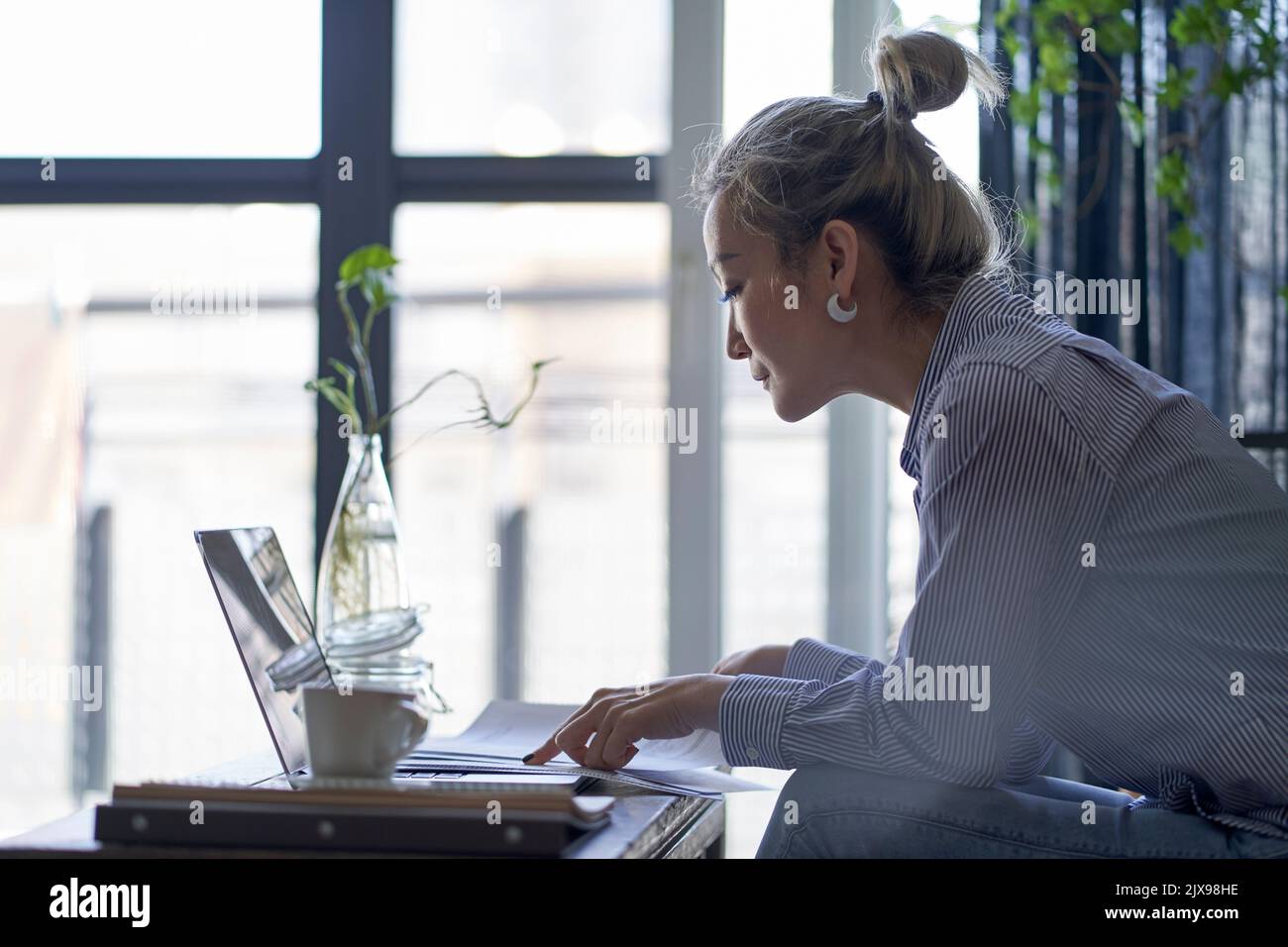 donna asiatica matura e professionale che lavora da casa utilizzando un computer portatile vista laterale Foto Stock