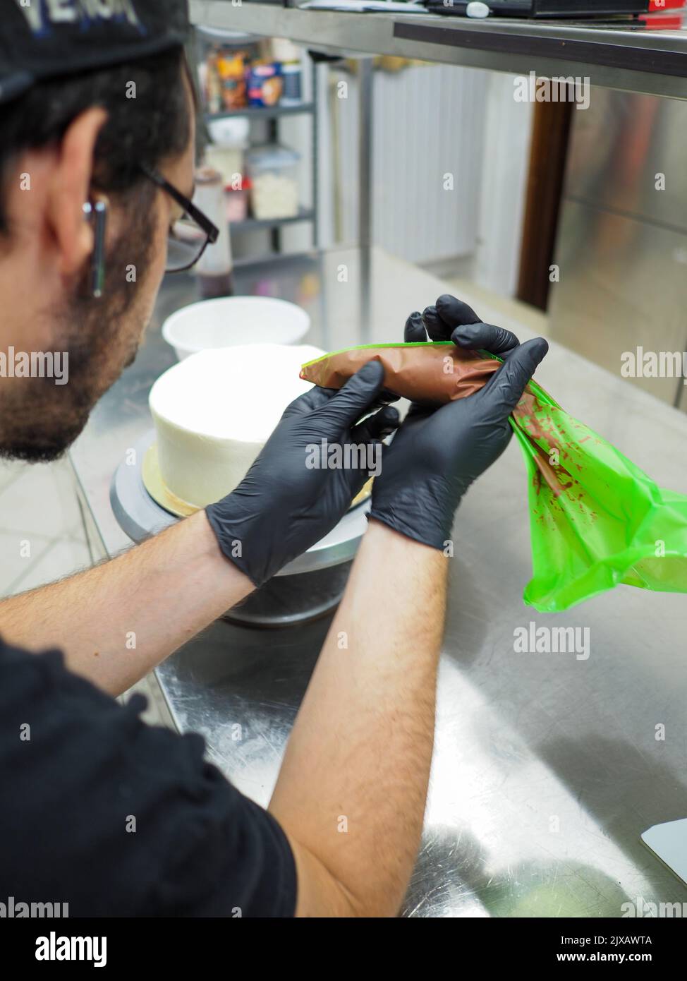 chef che prepara per glassare una torta rossa nel laboratorio di cucina professionale Foto Stock