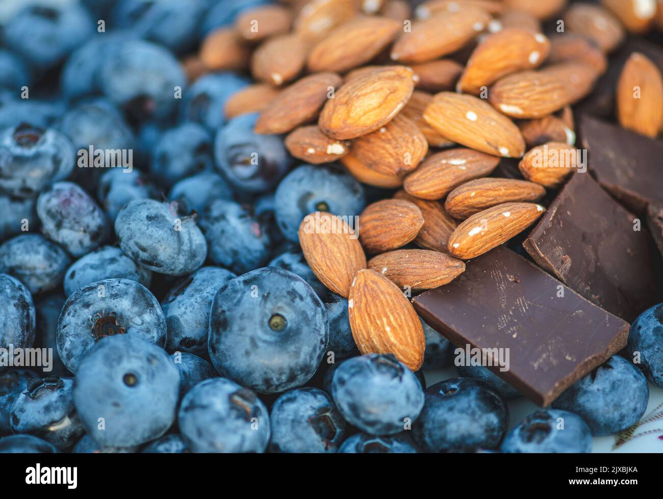 Mirtilli freschi, biologici e maturi, miscelati con mandorle secche non salate e pezzi di cioccolato fondente Foto Stock