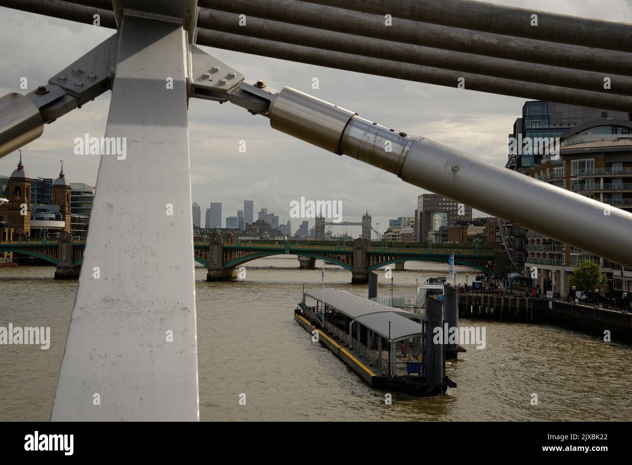 La città di Londra dal Millennium Bridge. I puntoni del ponte che incornicia la vista della città. Foto Stock