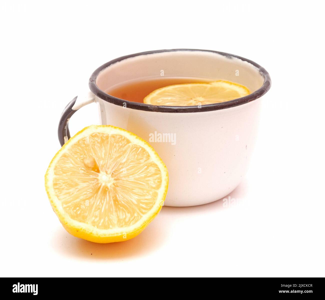 Vecchia tazza retrò in metallo con tè al limone e mezzo di limone isolato su sfondo bianco. Bevanda utile da autunno freddo Foto Stock