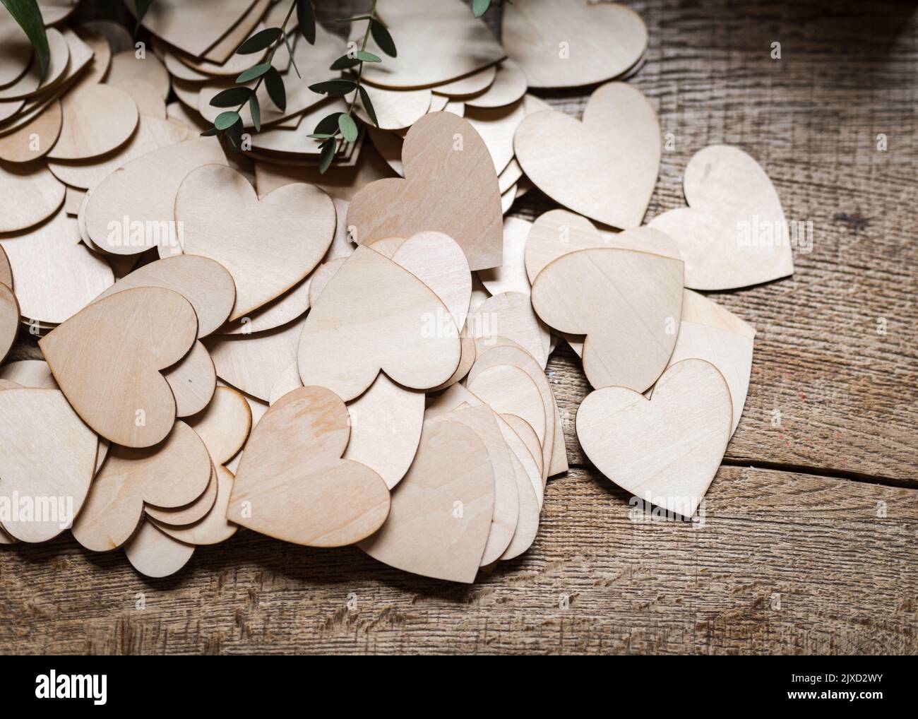 Cuori di amore di legno tagliato fuori e in un mucchio sulla vecchia tabella della quercia affinchè gli ospiti di nozze scrivano i messaggi sopra per la coppia appena sposata. Foto Stock