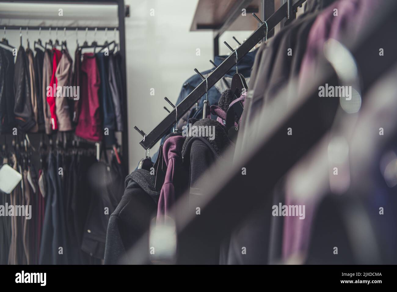 Primo piano di rack pieni di diversi tipi di vestiti su grucce in negozio di seconda mano. Tema per lo shopping dell'abbigliamento usato. Foto Stock