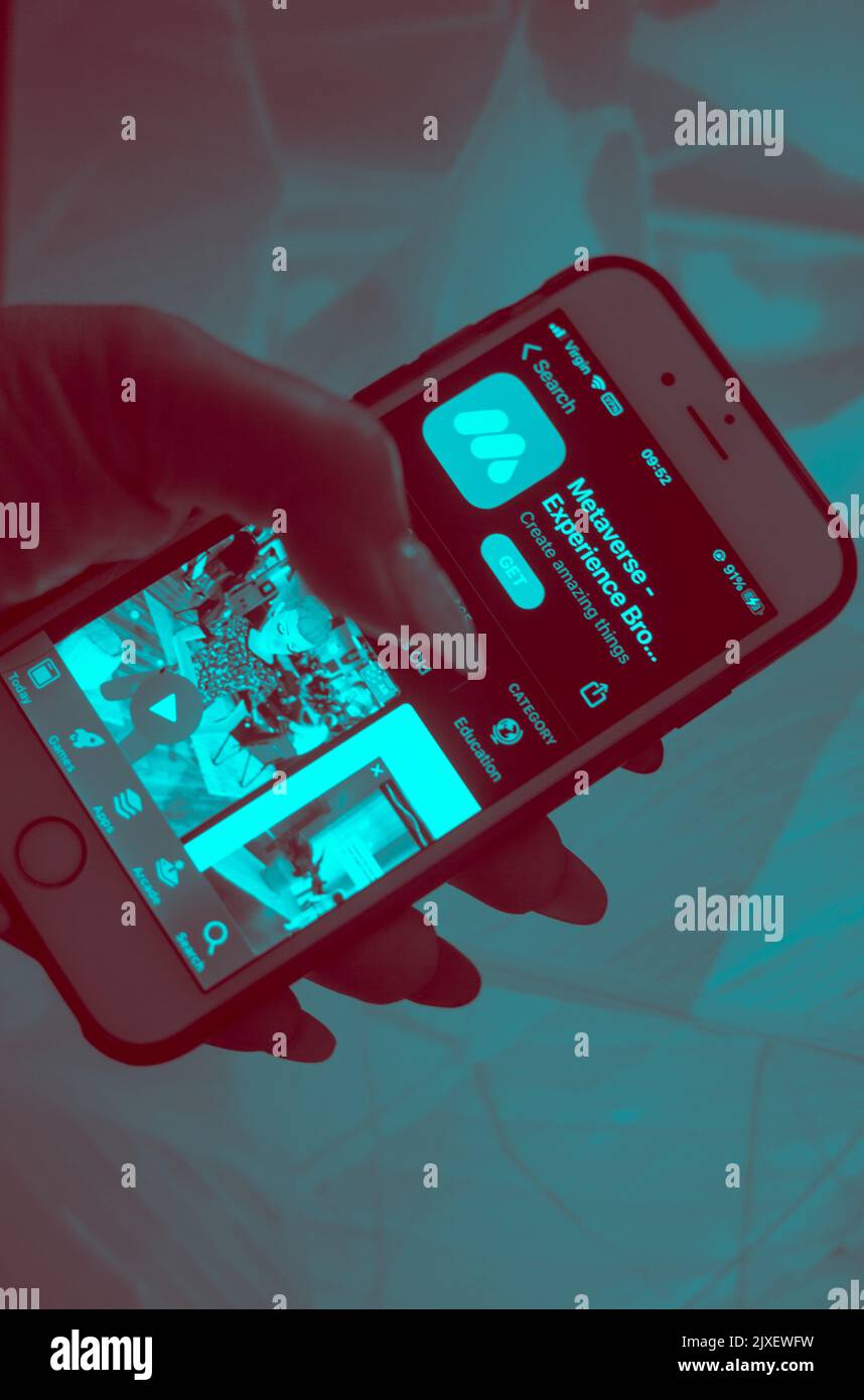 Metaverse Tech Lifestyle Concept - primo piano di una mano che tiene in mano un telefono cellulare con l'app Metaverse Experience sul display. Foto Stock
