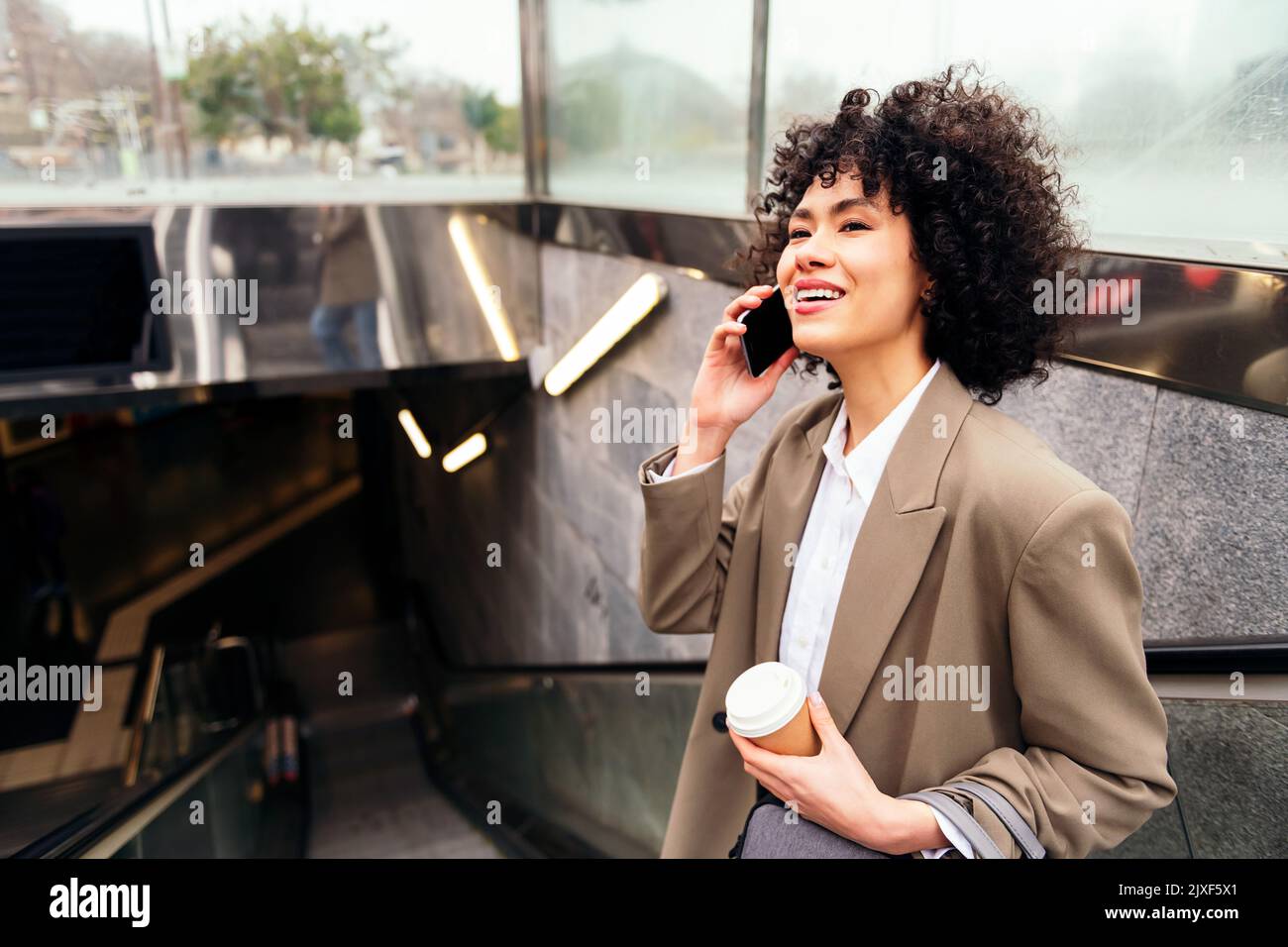 donna sorridente che parla per telefono sulla scala mobile Foto Stock
