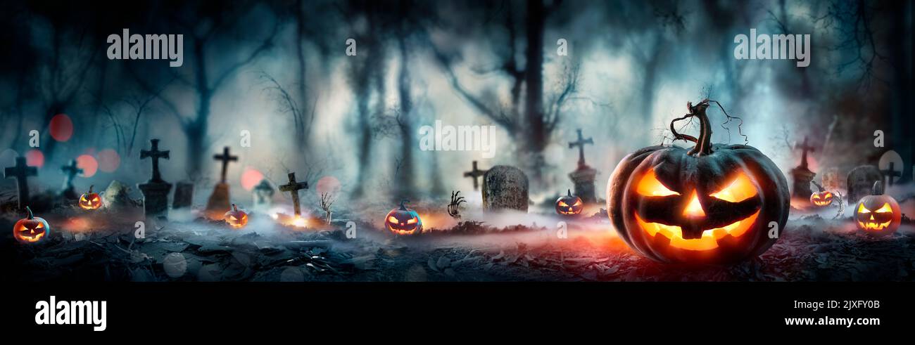 Halloween - zucche nella foresta spettrale con tombe di notte - sfondo sfocato astratto Foto Stock