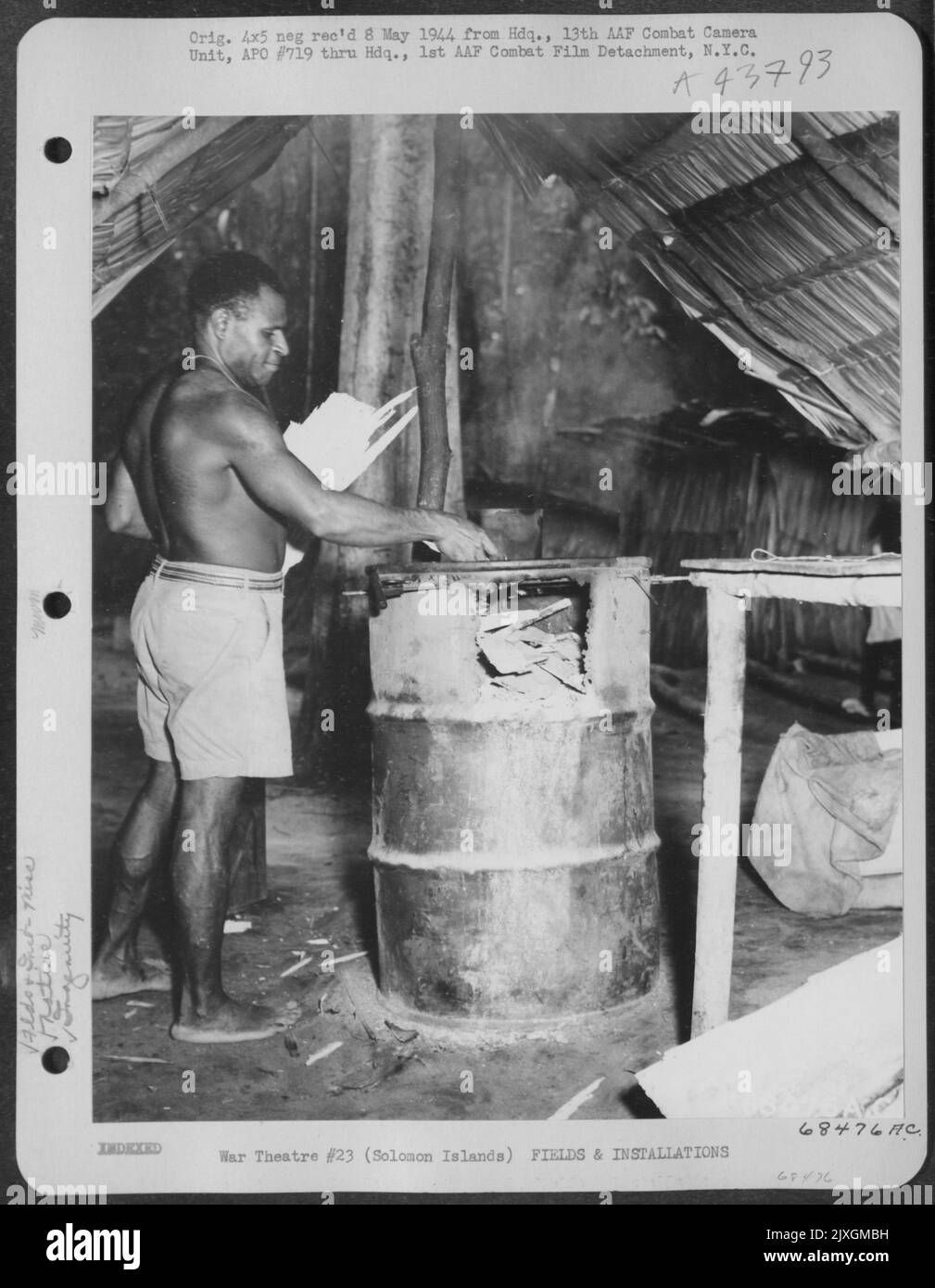 Dopo la pulizia mattutina da qualche parte nelle Isole Salomone, Un nativo Fils l'inceneritore (Un tamburo di combustibile scartato) con i detriti accumulati. Aprile 1944. Foto Stock