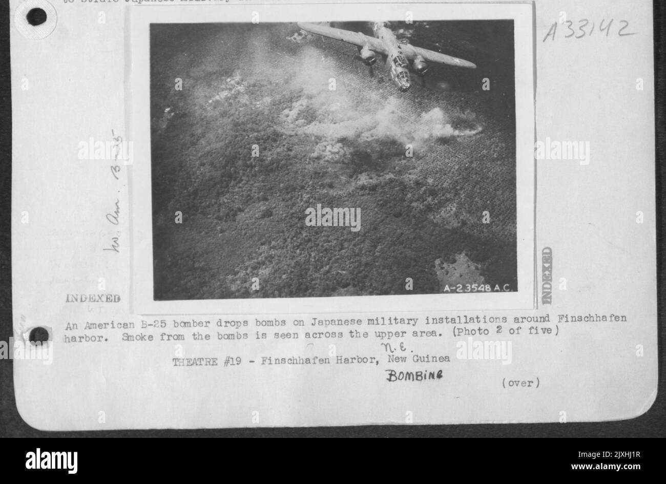 Un bombardiere americano B-25 rilascia bombe su installazioni militari giapponesi intorno al porto di Finschhafen. Il fumo dalle bombe si vede attraverso l'area superiore. Foto Stock