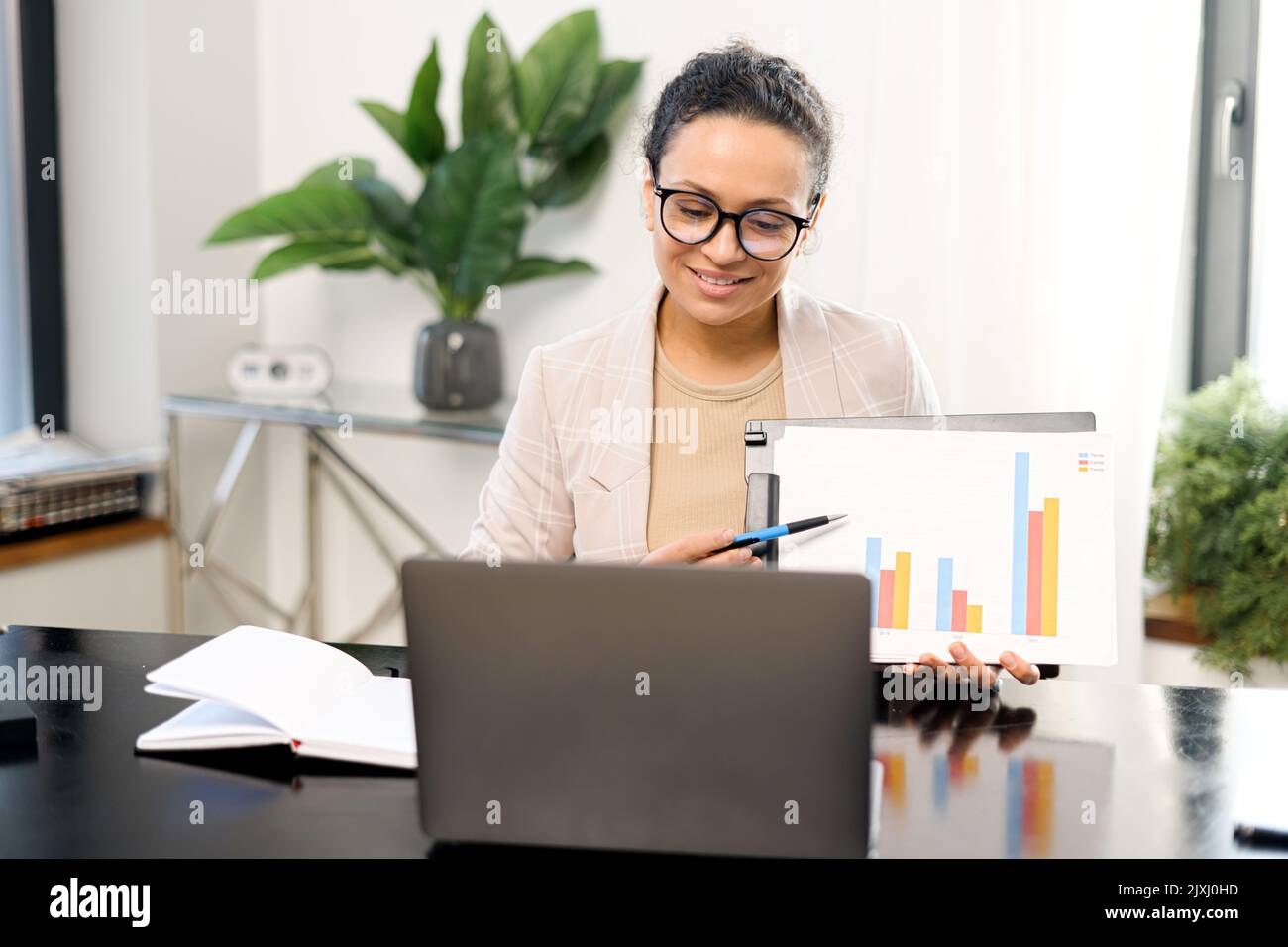Una donna d'affari ha partecipato a un webinar sulla guida di conferenze, tutor o business coach. Dipendente femminile di mezza età durante una riunione virtuale, che mostra i grafici nella webcam del notebook Foto Stock