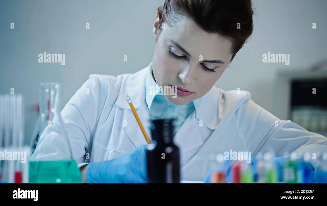 abbastanza scienziato che scrive il risultato dell'analisi in laboratorio, immagine di scorta Foto Stock