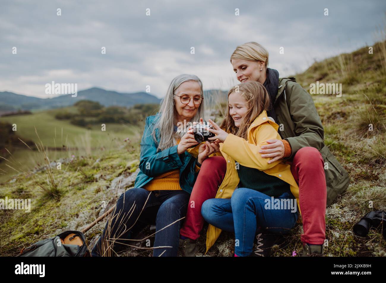 Donna anziana fotografando la figlia e la nipote in cima alla collina nel giorno d'autunno. Foto Stock