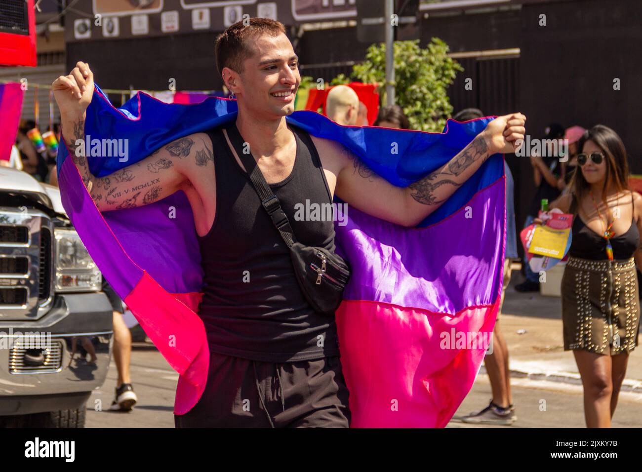 Goiânia, Goias, Brasile – 04 settembre 2022: Un giovane con una bandiera blu, viola e rosa, che balla felice a braccia aperte. Foto LGBTQIA+ Parade. Foto Stock