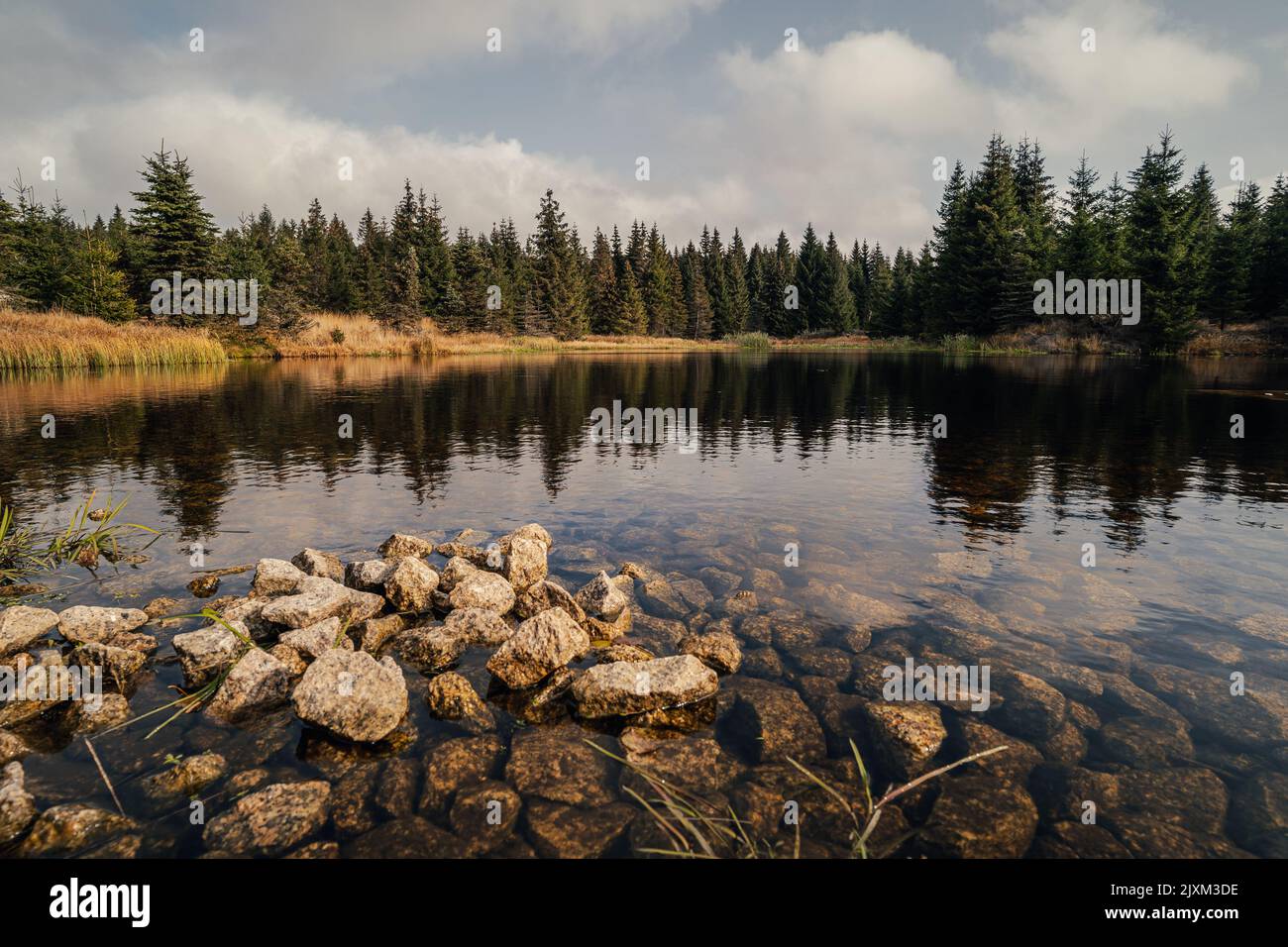 Vista su un lago di montagna scandinavo in autunno. Paesaggio in autunno, piccolo lago con rocce sulla riva. Alaska come paesaggio. Foto Stock