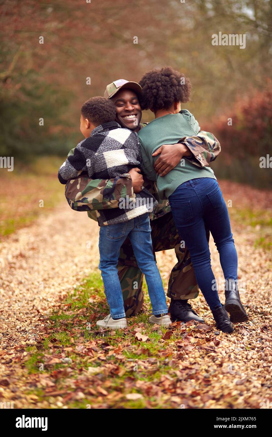 Soldato americano in uniforme con Kitbag ritorno a casa in partenza per la famiglia salutato da due bambini Foto Stock