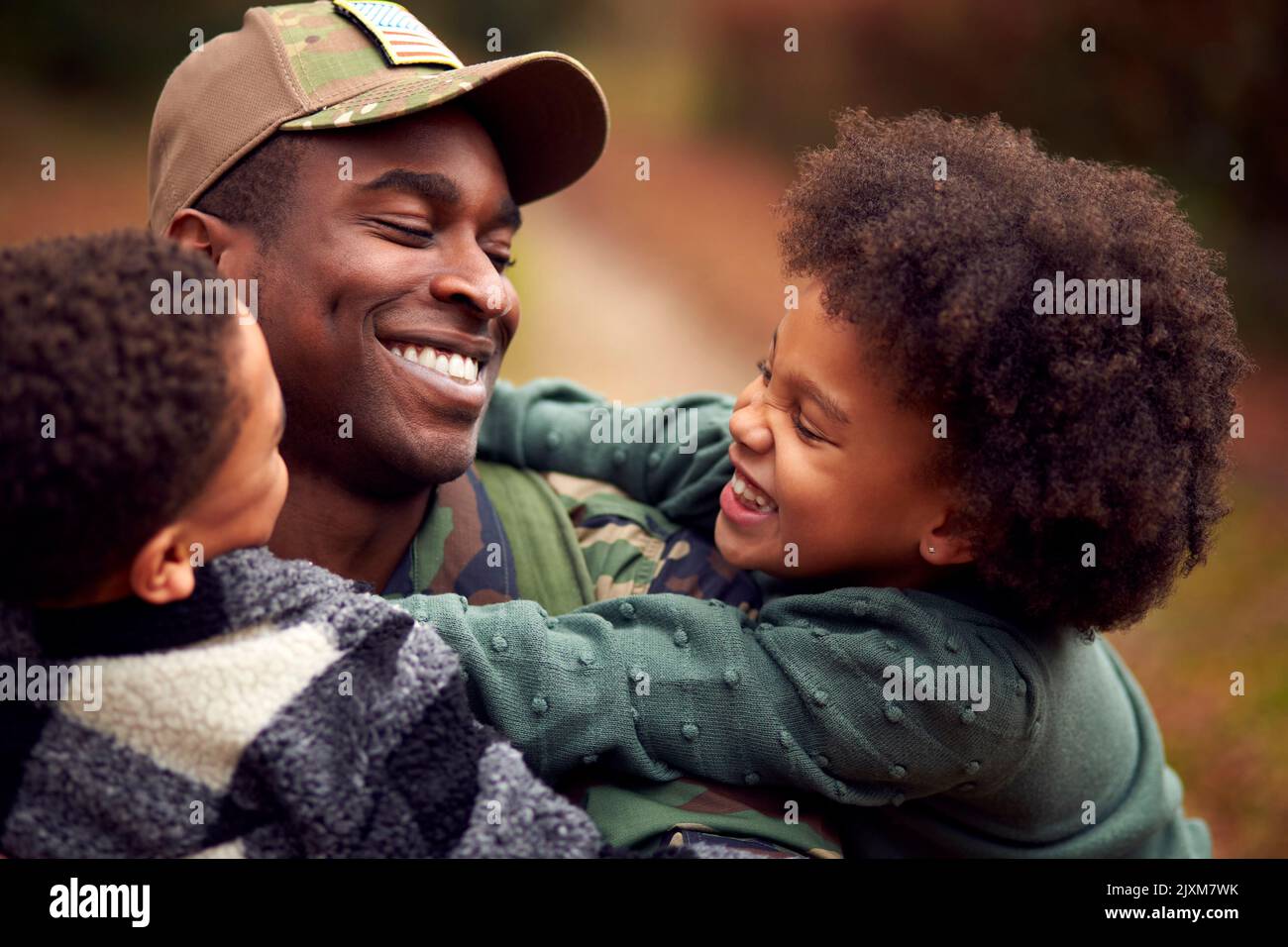 Soldato americano in uniforme ritorno a casa in partenza per la famiglia salutato da due bambini Foto Stock